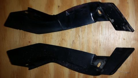 2015 Chevrolet new - Two black plastic trim pieces are shown against a wooden background.