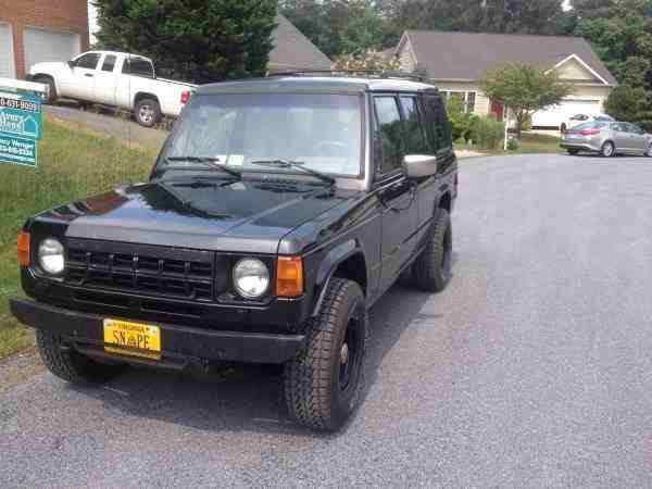 Black SUV with a custom license plate 'SNAPE' parked on a gravel driveway