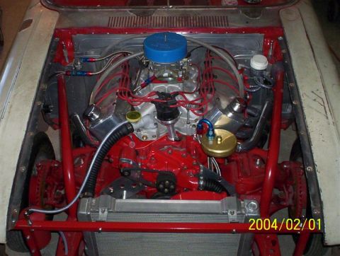 1963 Ford Falcon - The engine bay of a car is shown, a V8 engine with red accents and a prominent radiator.