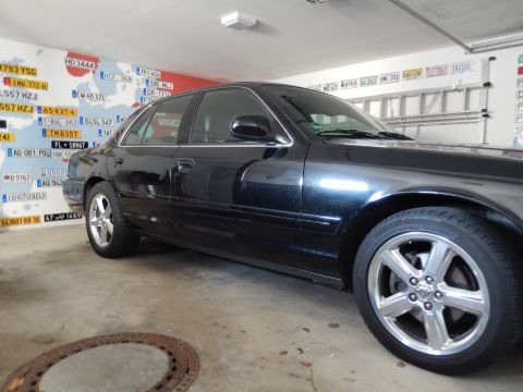 2003 Mercury Marauder - Side profile of a black 2003 Mercury Marauder in a garage with license plates on the wall.