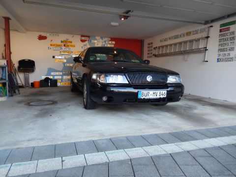 2003 Mercury Marauder - A black 2003 Mercury Marauder is parked inside a garage, with a collection of license plates displayed on the wall.