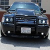 2003 Ford Crown Victoria - very small, blurry frontal photo of a dark sedan equipped with a black brush guard and a license plate.