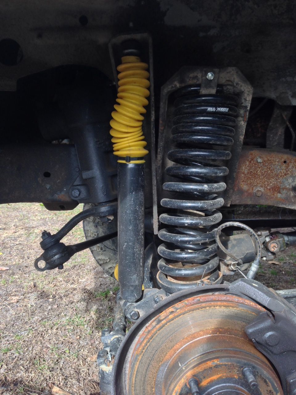 Front suspension components of a vehicle, showing a yellow shock absorber and black coil spring