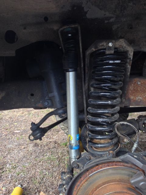 1979 Ford Bronco - The image shows the suspension system of a vehicle, including a shock absorber and coil spring, with some visible rust.