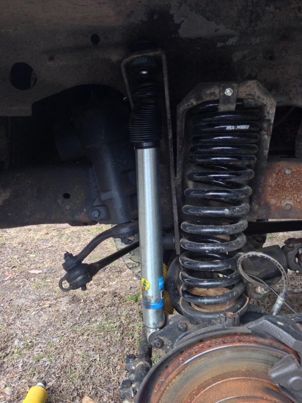 close-up of a vehicle's front suspension with a shock absorber and coil spring
