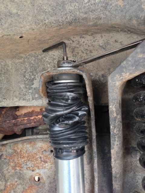 1979 Ford Bronco - A mechanic works on a vehicle's suspension system, focusing on a shock absorber's protective boot.