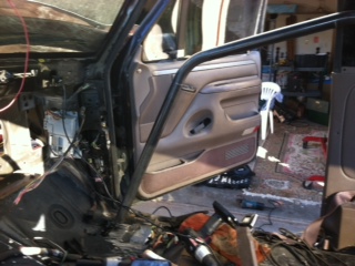 1995 Ford Bronco - The interior of a vehicle appears to be undergoing modifications, with a roll cage installed and wiring exposed.