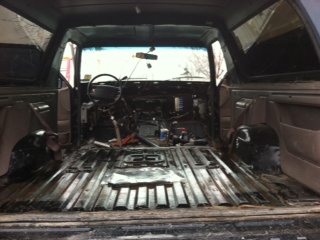 1995 Ford Bronco - The interior of an SUV is shown with most of its components removed, revealing the bare metal floor and dashboard.