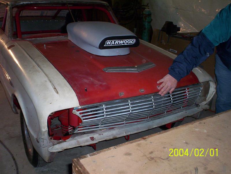 Ford project car front, red hood with Harwood scoop, chrome grille, in shop