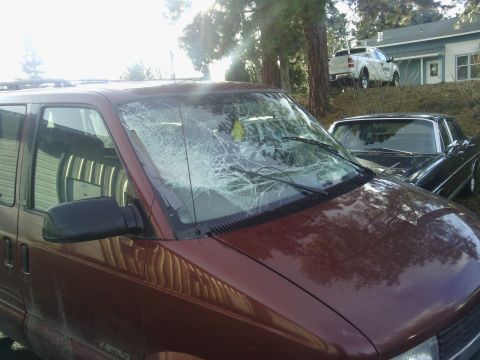 2000 Chevrolet Astro - This maroon van, identified as a 2000 Chevrolet Astro, shows significant damage to its windshield.