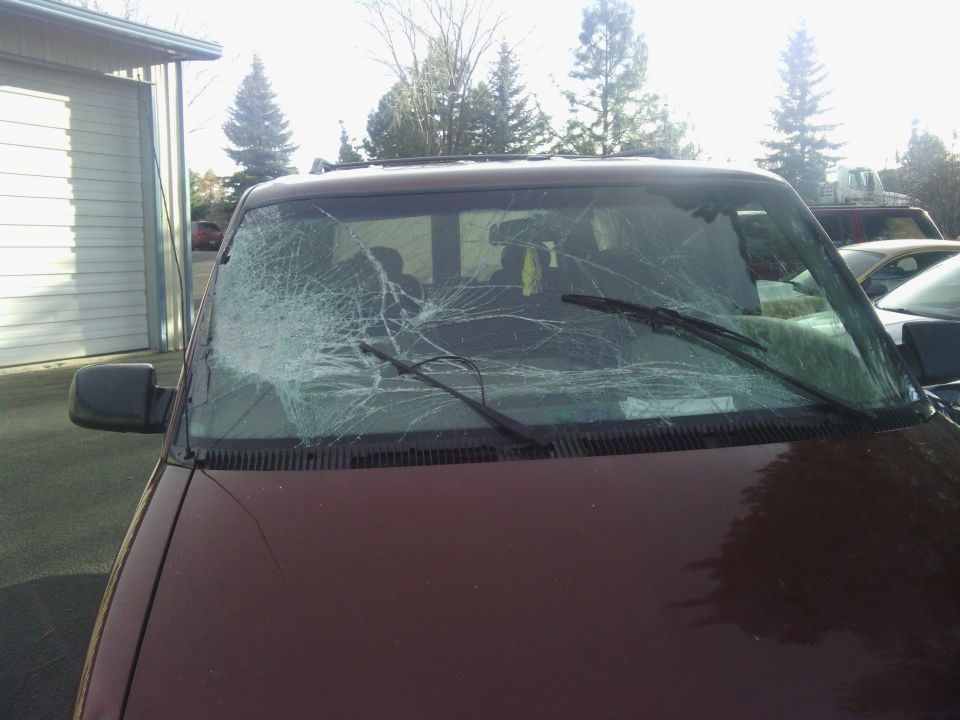 Maroon 2000 Chevrolet Astro van with a severely cracked windshield, parked outdoors