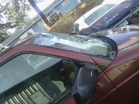 2000 Chevrolet Astro - The front of a maroon van is shown with a severely damaged windshield and a dark side mirror.