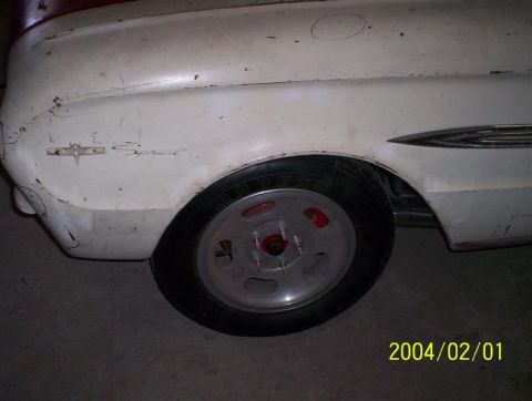 1963 Ford Falcon - Close-up of a white 1963 Ford Falcon's side, showing the fender, wheel, and chrome trim, with visible signs of age.