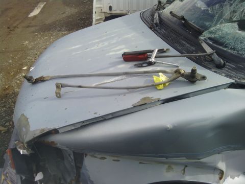2000 Chevrolet Astro - Windshield wiper mechanism and tools are laid out on the hood of a damaged vehicle.