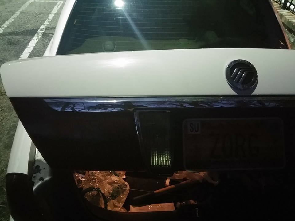 Trunk of a 2000 Mercury Grand Marquis with the trunk open. License plate is visible