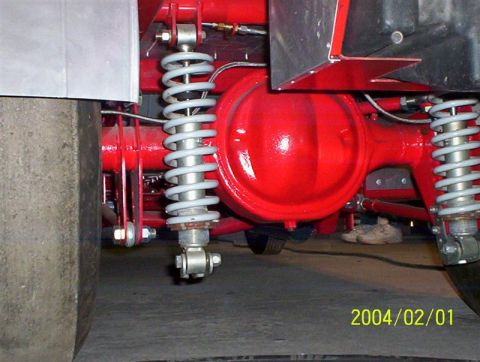 1963 Ford Falcon - Close-up view of a vehicle's rear axle and suspension system, showing custom red paint and dual shocks.