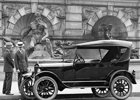 1909 Ford Model T - A black touring car from the mid-1920s is parked in front of a stone sculpture, with two men in hats observing it.