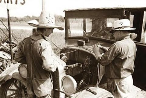 1909 Ford Model T - Men attend to a vintage automobile, its hood open, in an outdoor setting.
