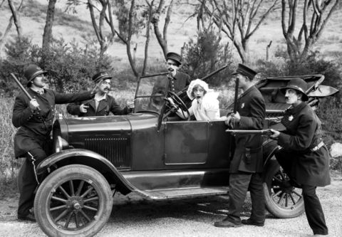 1909 Ford Model T - A staged scene depicts a woman being apprehended by officers next to a vintage automobile.