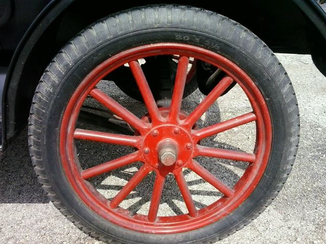 Red spoked wheel on a black tire, part of a 1909 Ford Model T
