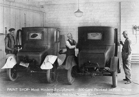 1909 Ford Model T - Two 1909 Ford Model T cars are seen in a paint shop, with workers attending to them.