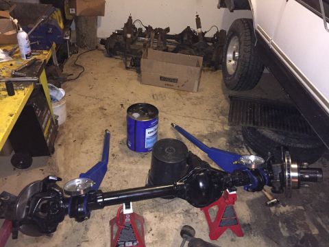 1994 Ford Bronco - Vehicle axle assembly on jack stands in a workshop setting with various parts around.