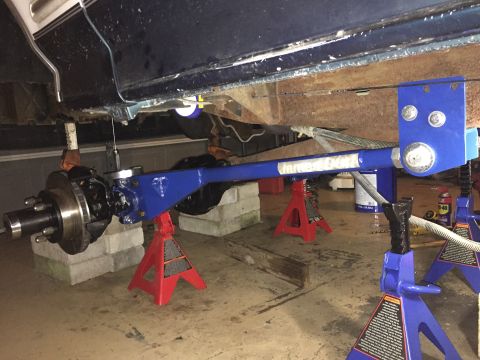 1994 Ford Bronco - The underside of a vehicle is supported by jack stands while a blue suspension part is visible.