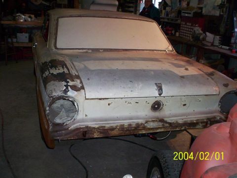1963 Ford Falcon - A car in a garage shows signs of rust and disrepair, with one headlight missing.