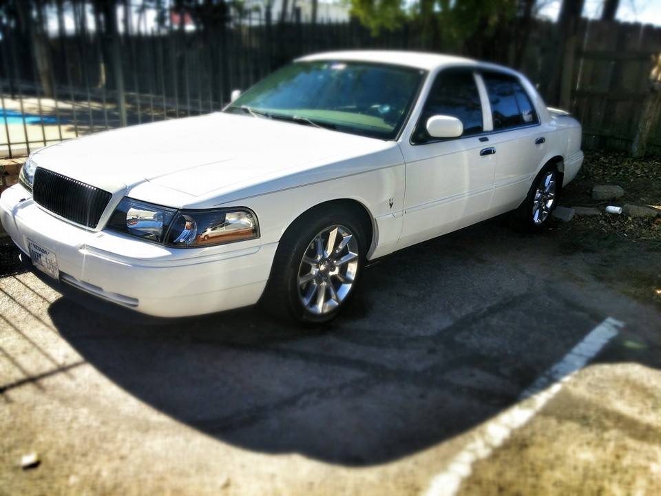 White sedan with chrome wheels parked on asphalt, showing front quarter view