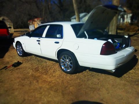 2000 Mercury Grand Marquis - A white sedan is parked outdoors with its trunk open, revealing some items inside.