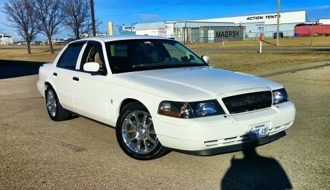 2000 Mercury Grand Marquis - A white 2000 Mercury Grand Marquis is parked outdoors on a sunny day, showing its front and side profile.