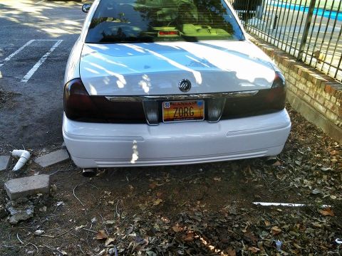 2000 Mercury Grand Marquis - The rear of a white sedan is shown parked on a dirt lot with fallen leaves.