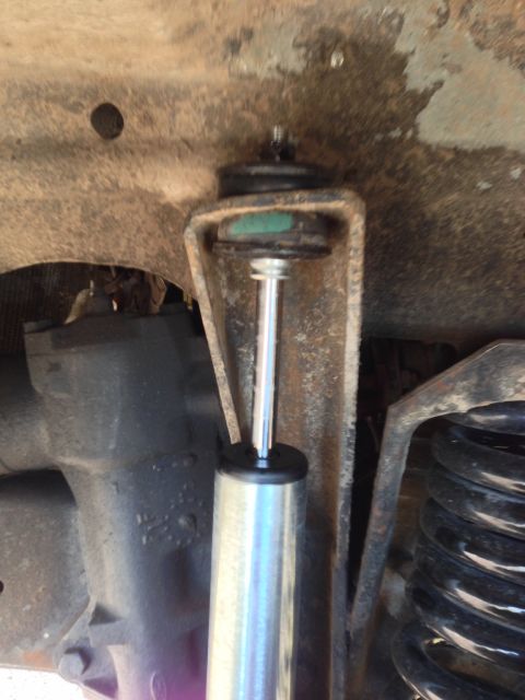 1979 Ford Bronco - Close-up view of a vehicle's shock absorber and suspension spring, with visible rust on the frame.