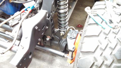 1967 Ford F-250 - A close-up view of a truck's chassis, suspension components, and a large tire, with tools resting on the tire.