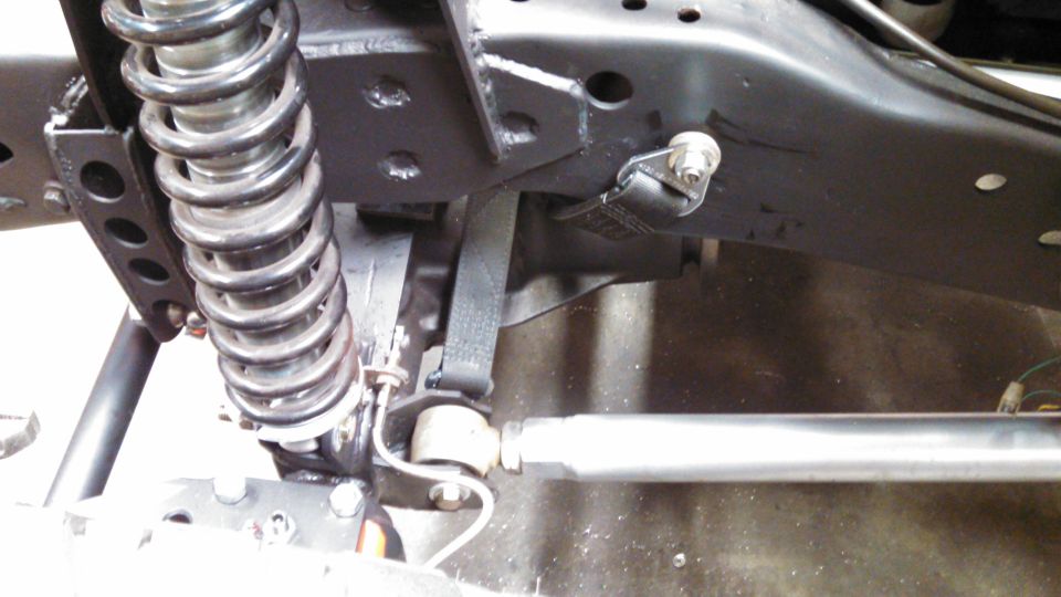 Close-up of a truck's frame showing a coil spring, shock absorber, and suspension linkage