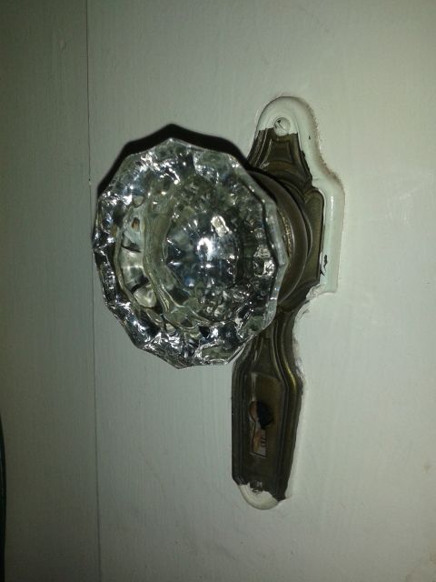 1990 Ford Bronco - Close-up of an antique glass doorknob and its brass mounting plate.