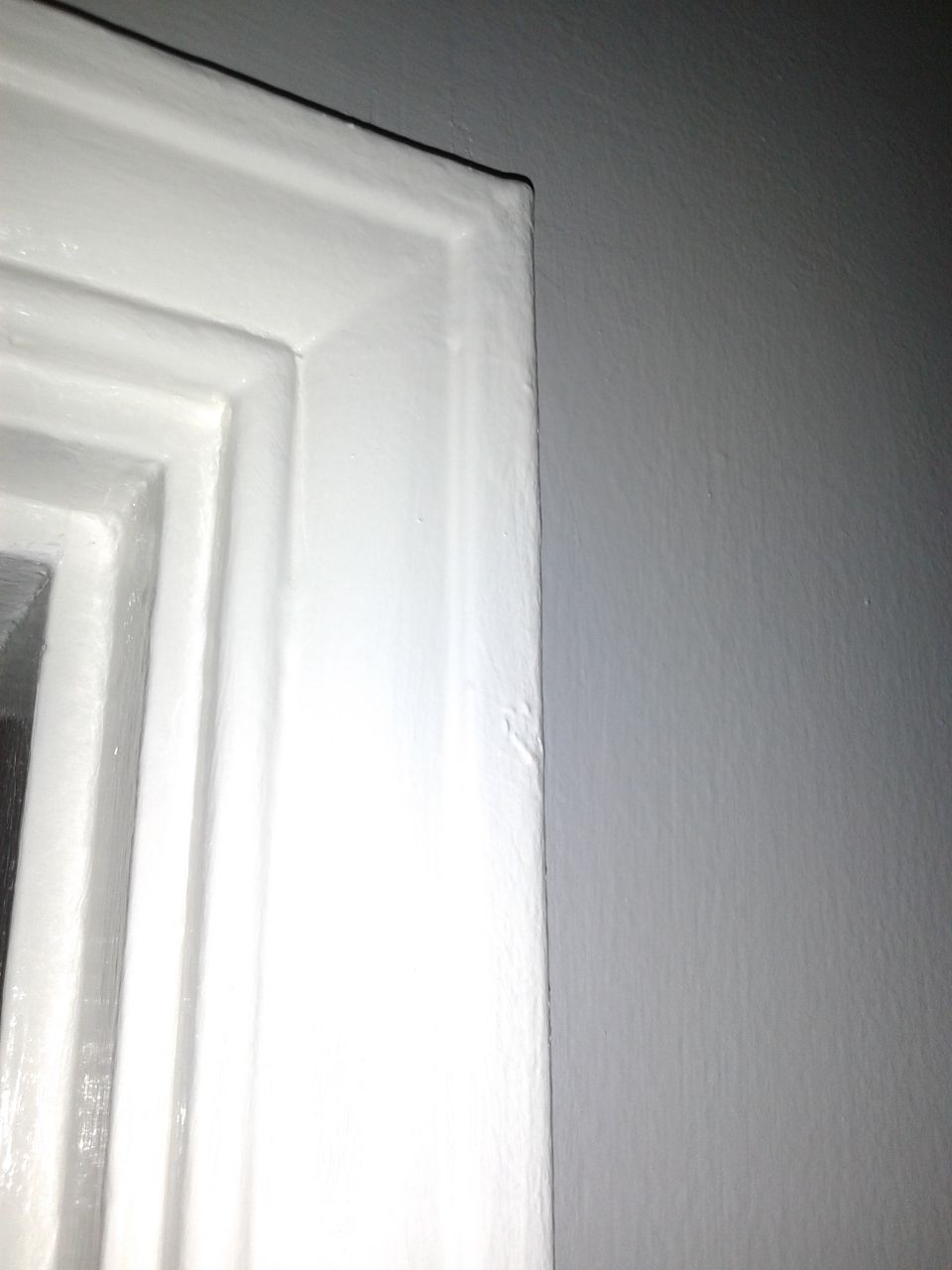 close-up of a white painted door frame against a gray wall