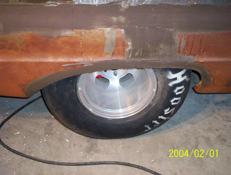 Bare-metal rear quarter with widened wheel lip over an aluminum wheel and Hoosier drag slick