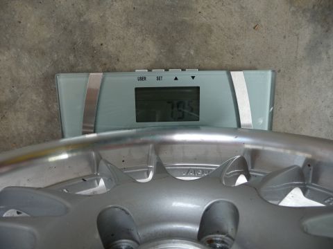 1993 Mazda MX-3 - A silver alloy car wheel is weighed on a digital scale, showing a reading of 7.95.