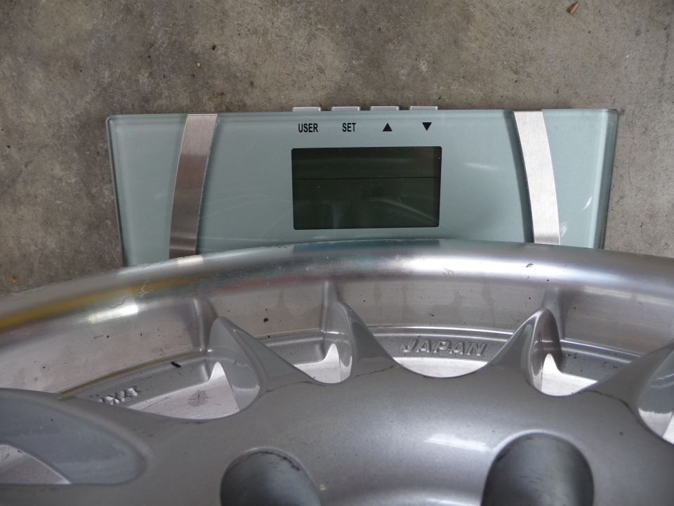 Close-up of a silver car wheel with 'JAPAN' visible, resting on a digital scale