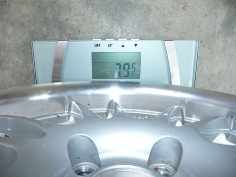 1993 Mazda MX-3 - A car wheel is placed on a digital scale, which displays its weight as 7.95 kilograms.