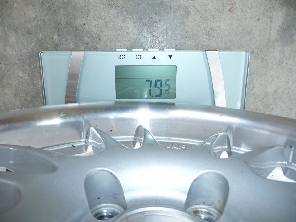 Car wheel being weighed on a digital scale showing 7.95 kg