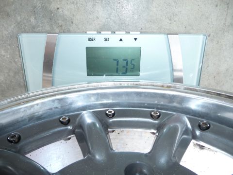 1993 Mazda MX-3 - A single alloy wheel is weighed on a digital scale, showing a reading of 7.35.