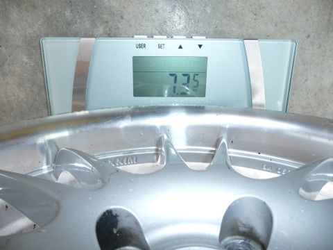 1993 Mazda MX-3 - A wheel is being weighed on a digital scale, which displays a weight of 7.75 kg.