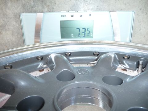 1993 Mazda MX-3 - A car wheel is weighed on a digital scale, showing a weight of 7.35 kilograms.