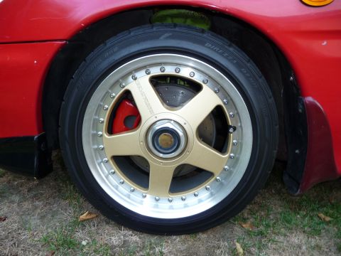 1993 Mazda MX-3 - Aftermarket wheel and tire assembly with visible brake components.