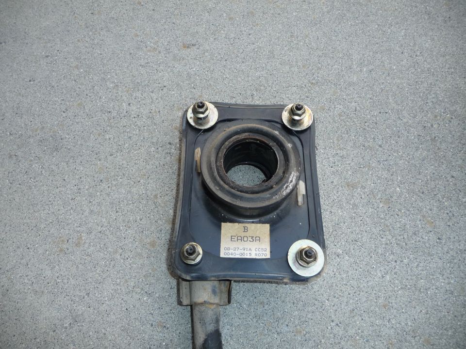 Black suspension component with rubber bushing and four bolts. Label reads EA03A