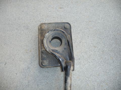 1993 Mazda MX-3 - A close-up view of a black suspension component, possibly a bracket or mount, against a concrete surface.