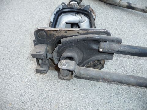 1993 Mazda MX-3 - Close-up of a car's suspension linkage assembly, showing metal rods and a rubber boot.
