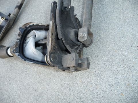 1993 Mazda MX-3 - Close-up of a vehicle's gear shifter assembly, showing the mechanical linkage and rubber boot.